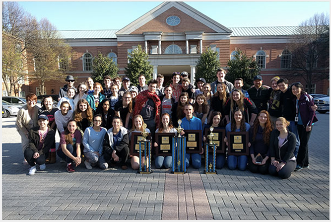 music students posing for group photo in front of brick building