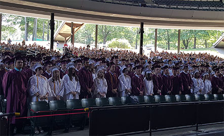 students wearing maroon and white caps and gowns at graduation