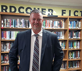 tim brunson standing in front of a bookcase smiling