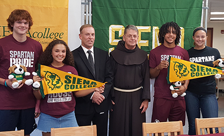 four students with siena college signs up with superintendent and siena college representative. 