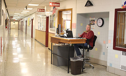 MS security monitor sits at a desk in the open hallway