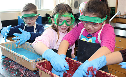 students wearing blue rubber gloves to touch Oobleck (Science Slime)