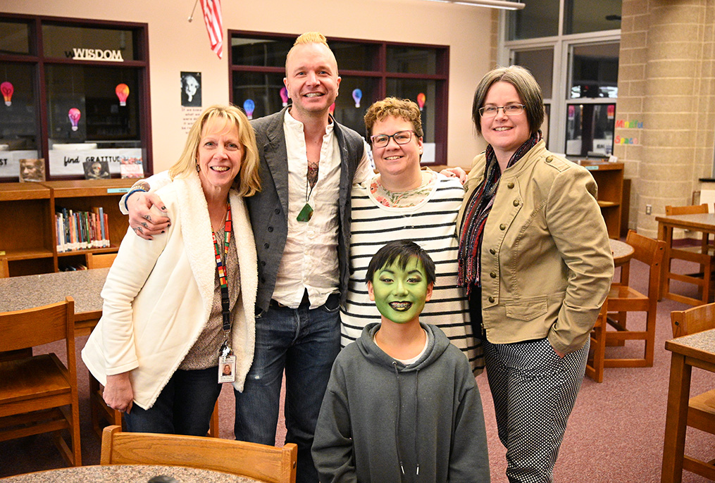 adults standing with student wearing green face makeup