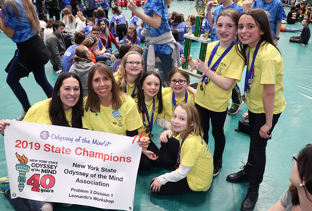 two adults and 6 students posing with winning trophy and championship sign