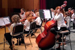 students playing in orchestra concert on stage