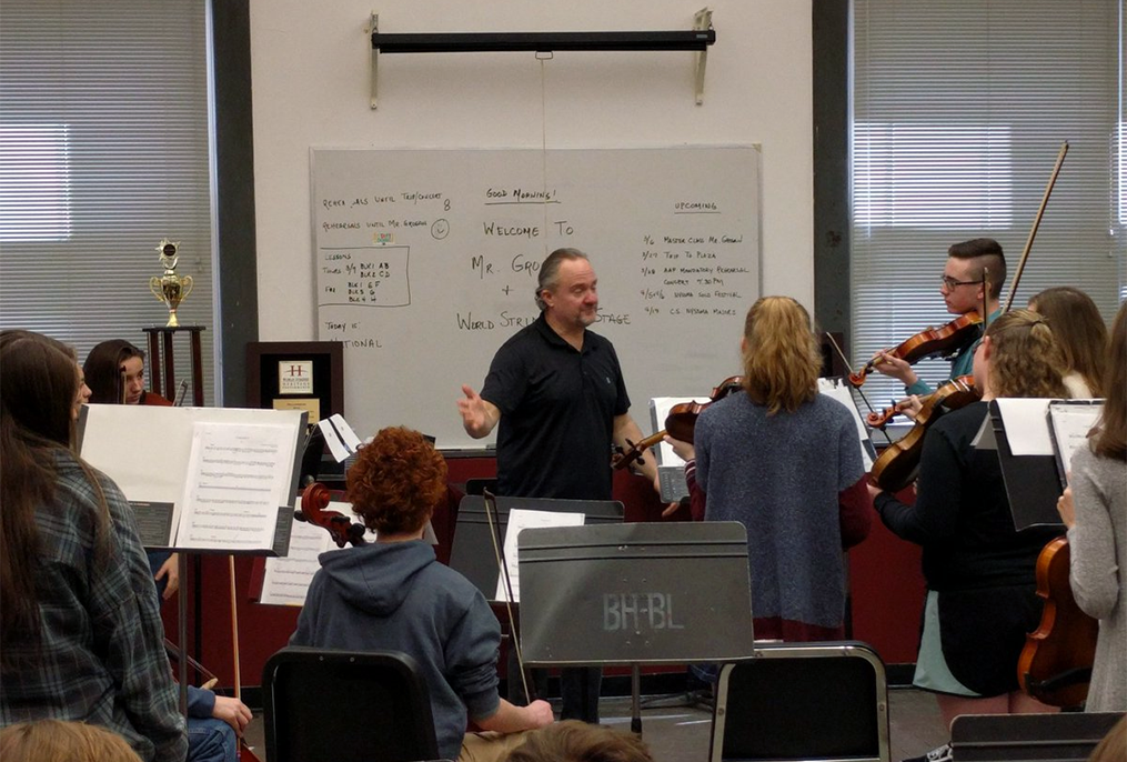 conductor working with high school orchestra students
