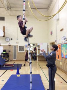 student climbing a rope in gym