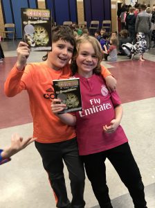 two students arm in arm holding up the same book