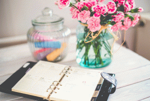 paper calendar next to pink flowers in a vase