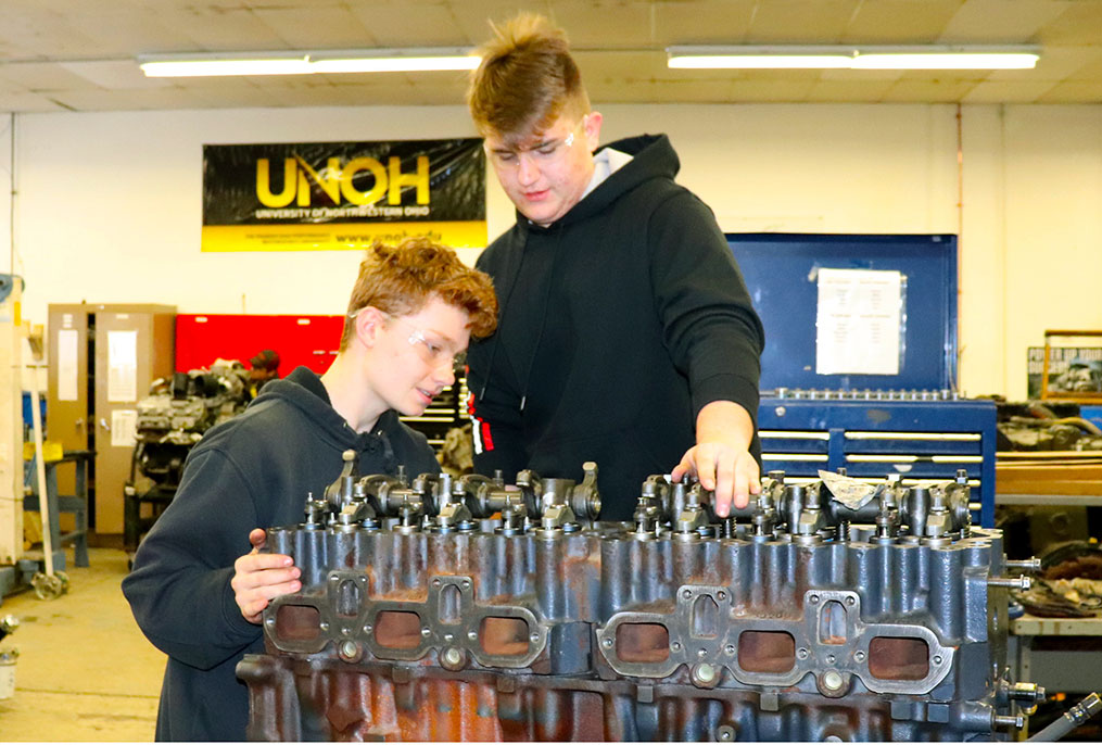 two students looking at an engine