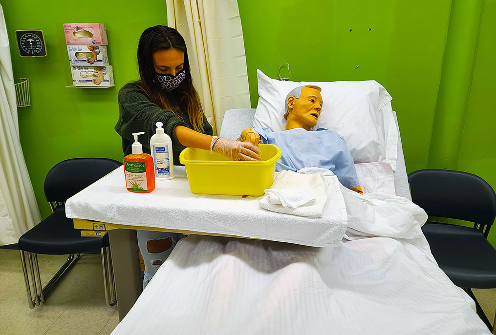 student working with a demo patient who is in a bed