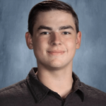 student with brown hair in a brown shirt smiling