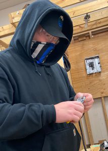 student wearing blue holding holding a tool