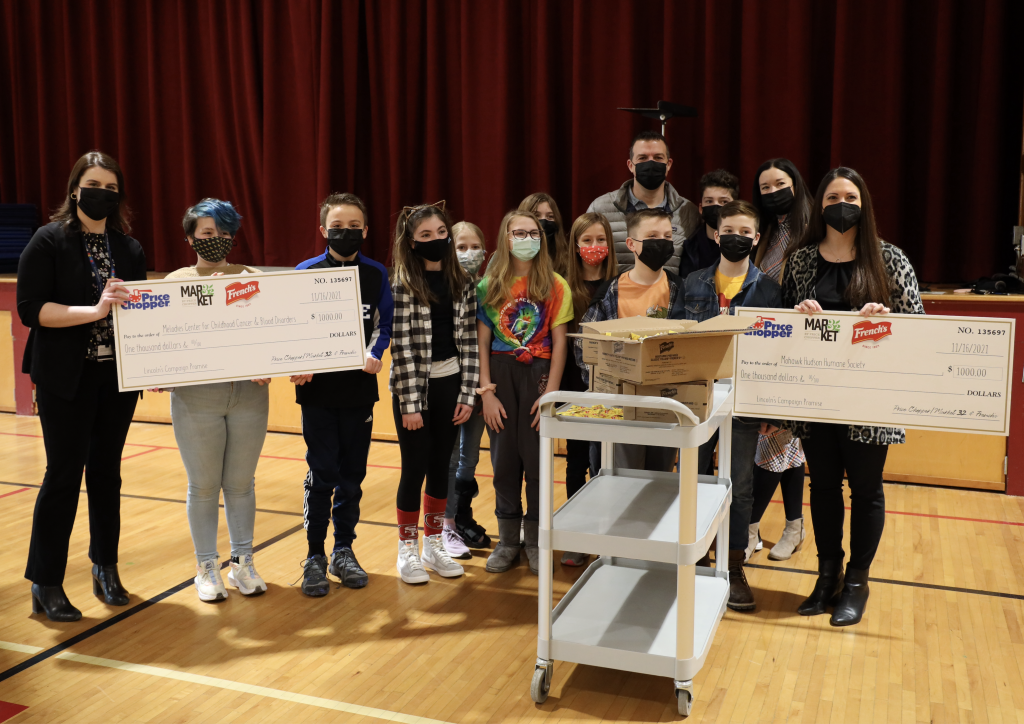 a group of people standing with two large donation checks