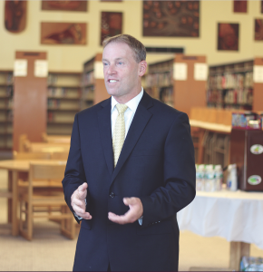 superintendent wearing a blue suit coat and a yellow tie