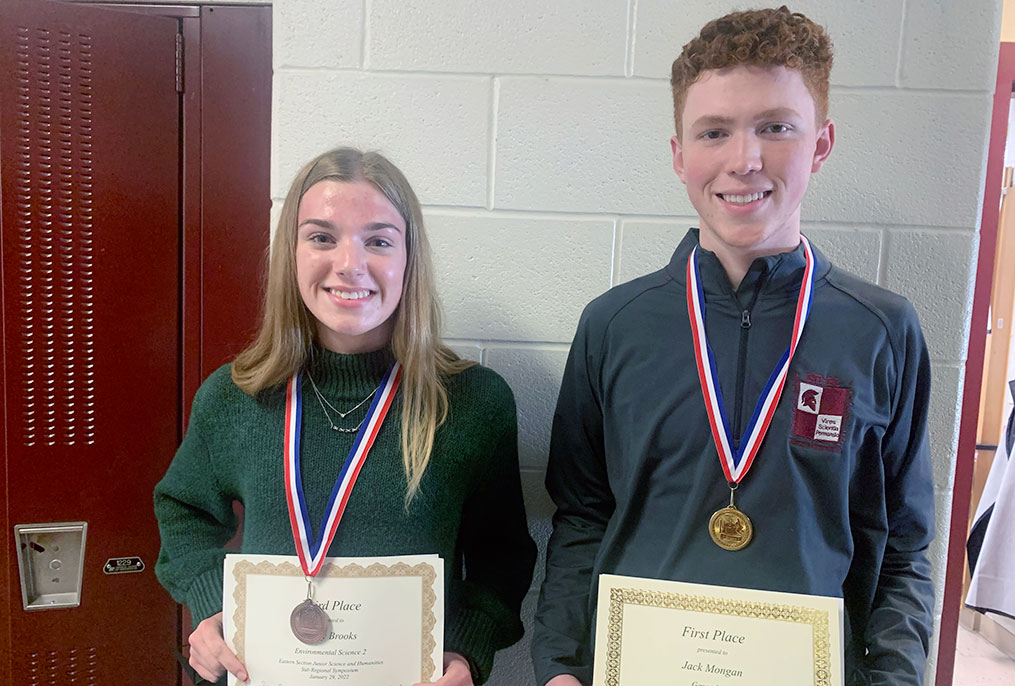 two students wearing medals and holding certificates