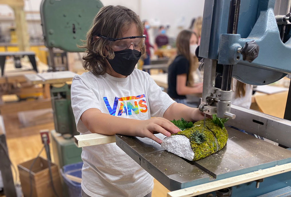 a student using a saw on a model