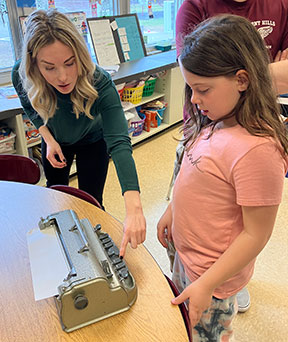 teacher demonstrating to a student the braille machine