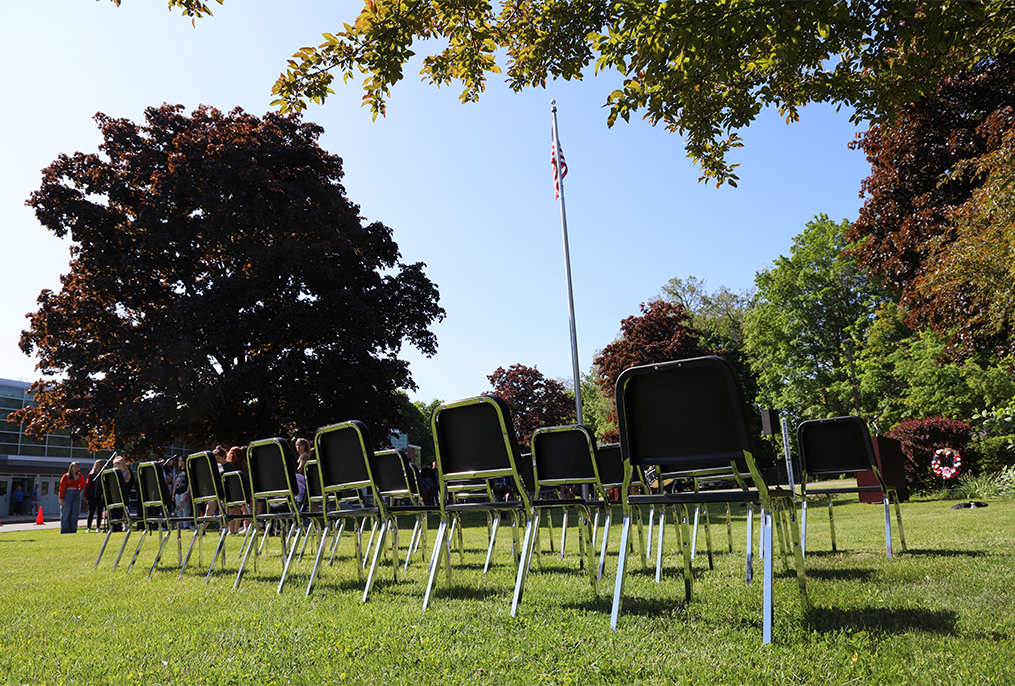 21 empty chairs with American flag in the background