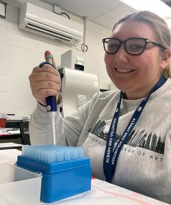 student in a science lab holding a pipette