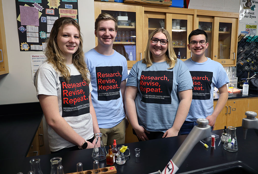 four students standing in a science lab