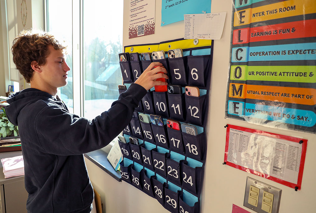 A student putting their cell phone in a holder.