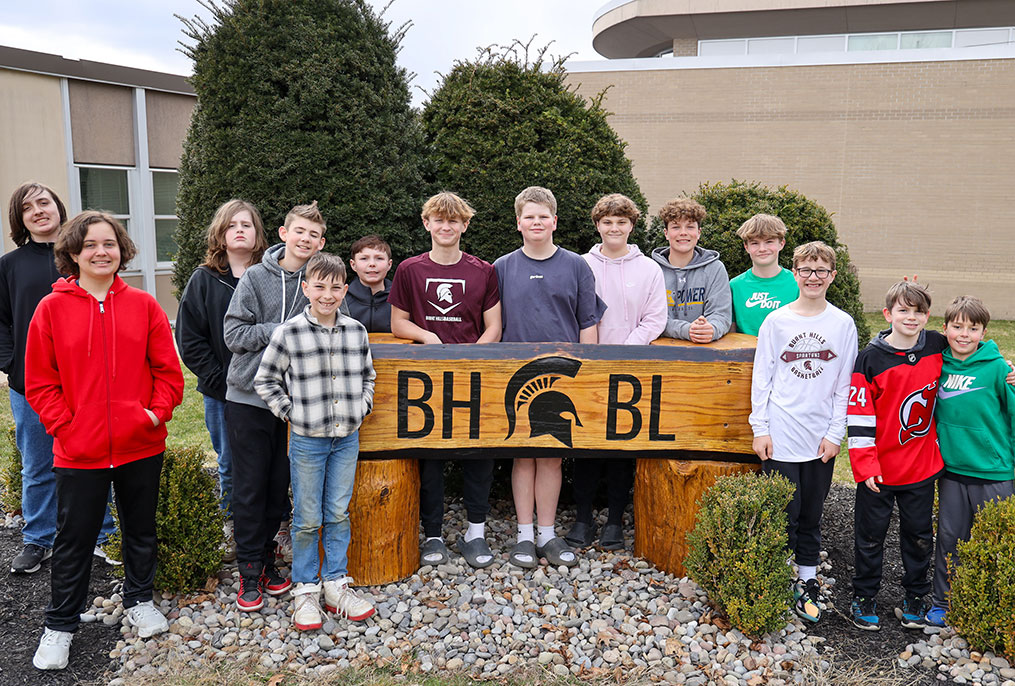 Middle School students out in front of their wooden sign.