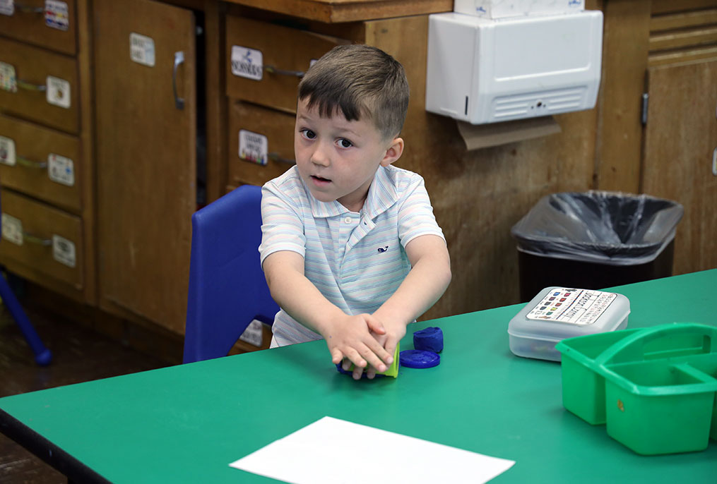 A kindergarten student playing with Play-Doh.