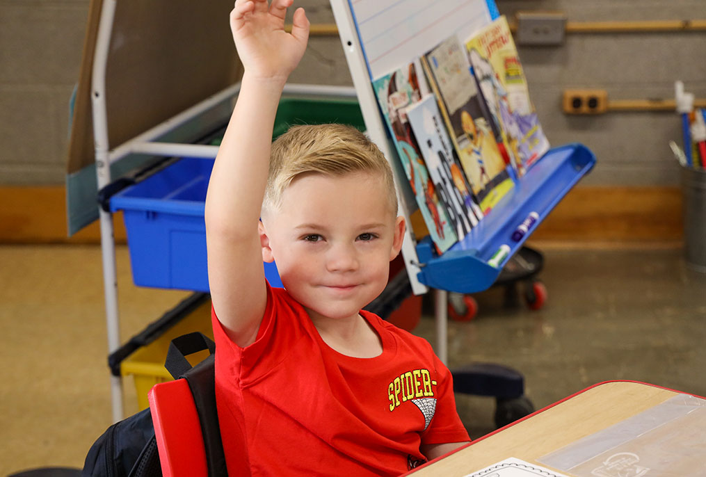 A student raising his hand in class.