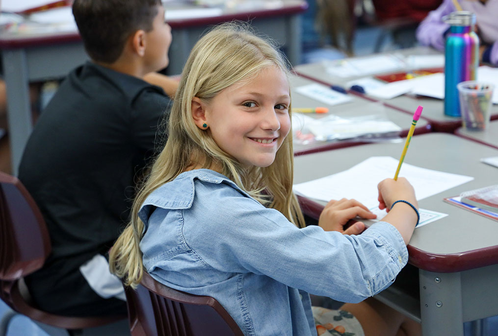 A student smiling while doing work.