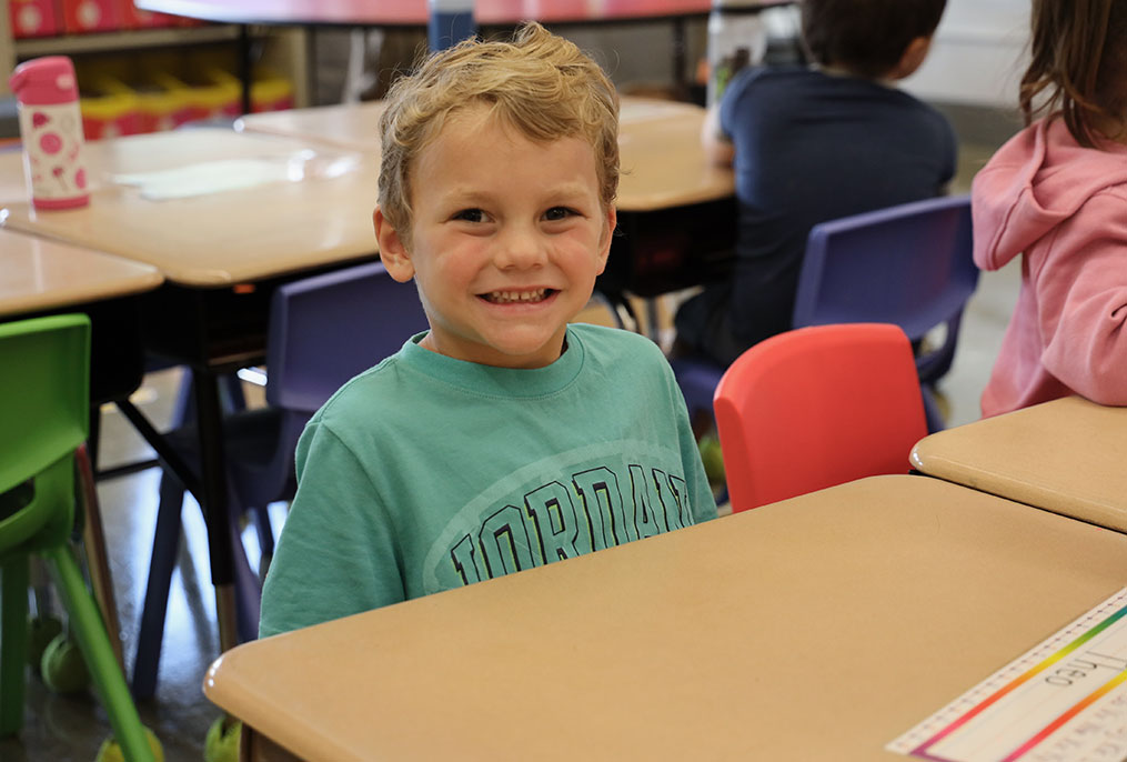 A kindergarten student smiling while at school.