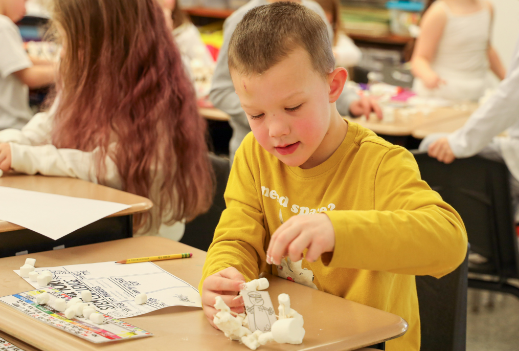 A student building a structure out of marshmallows.