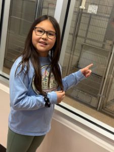student pointing to an animal's home at the shelter