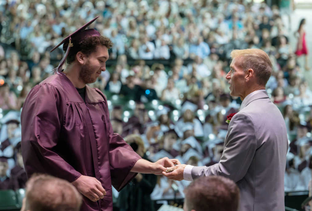 A student shaking hands with the superintendent at the BHBL graduation.