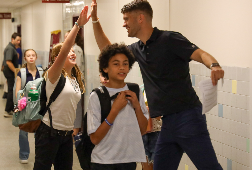 A teacher giving a student a high five in the hallway.