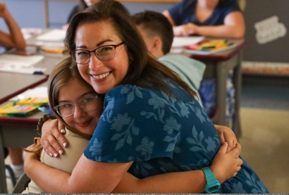 BHBL Frist Day SES A teacher hugging a student in class