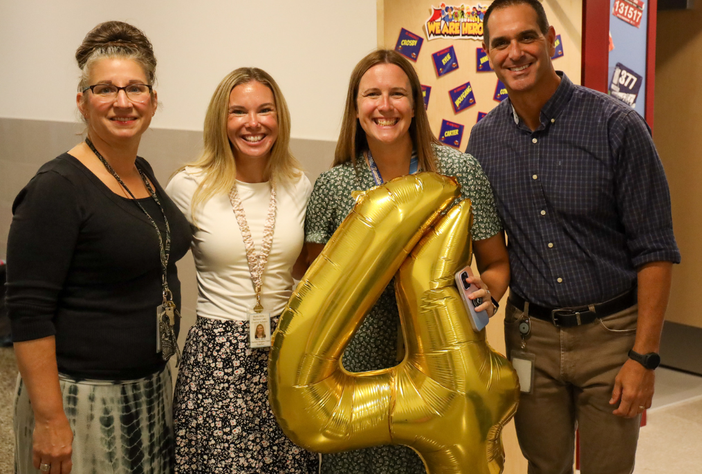 Teachers holding a the number four balloon.